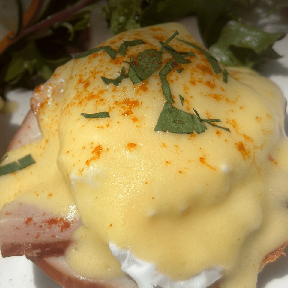 Close-up of Brookland Pint's Eggs Benedict, topped with hollandaise sauce, paprika, and herbs.