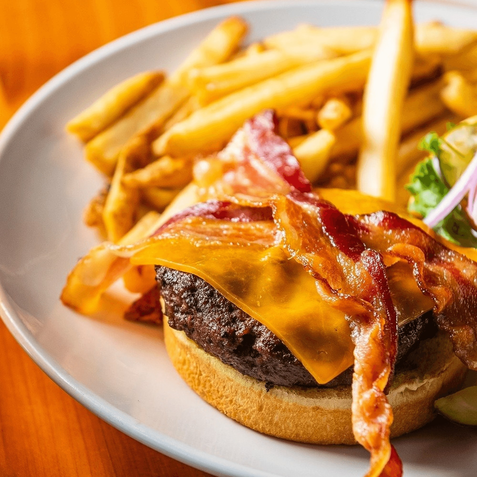 Brookland Pint's bacon cheeseburger with melted cheddar, crispy bacon, and a side of golden fries.
